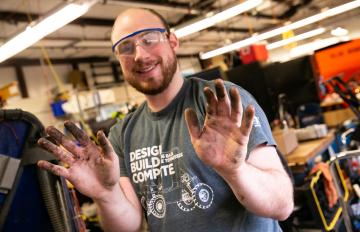 Steven from the Olin Baja teams shows off dirty, greasy hands after working on the baja vehicle